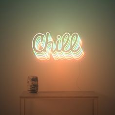 a neon sign that reads chill on top of a table next to a vase and lamp