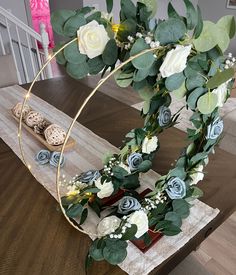 an arrangement of flowers and greenery is arranged on a wooden table in the middle of a room