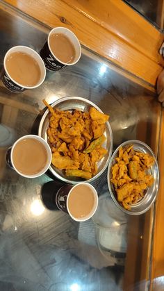 there are several cups of coffee and some food on the table with sauces in them