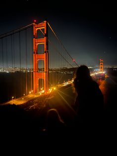 the golden gate bridge is lit up at night with lights shining on it's sides