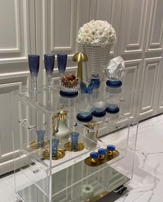 a clear shelf filled with blue and white vases on top of a marble floor