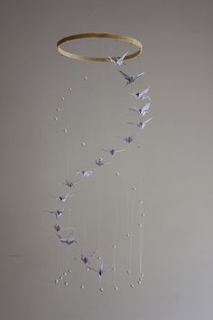 a wind chime with paper cranes hanging from it's sides and pearls on the strings