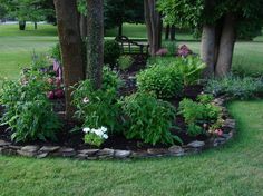 a flower garden in the middle of a park with trees and flowers growing around it