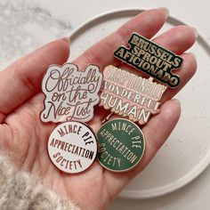 a person holding several pins in their hand with the words on them, including one that says