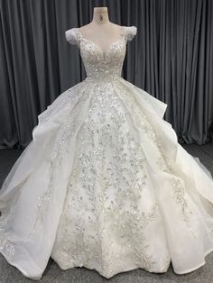 a white ball gown on display in front of curtains