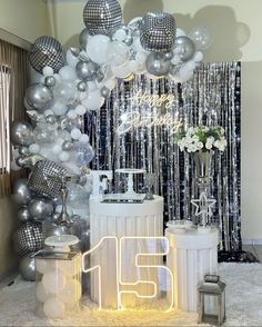 a party with balloons, silver and white decorations and a large number 15 sign in front of it