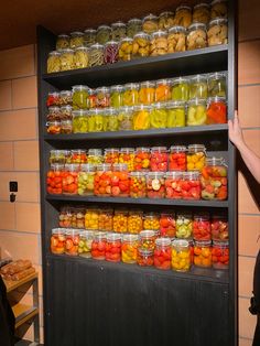 a woman standing in front of a shelf filled with lots of fruits and veggies