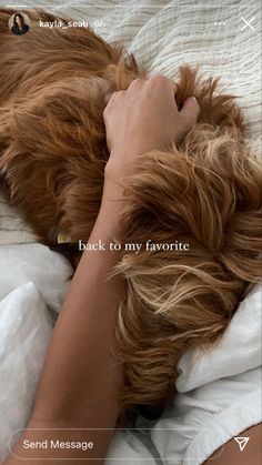 a woman laying on top of a bed with her hand over the head of a dog