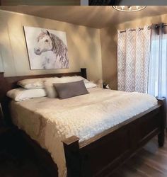 a large bed sitting in a bedroom next to a window with curtains on both sides