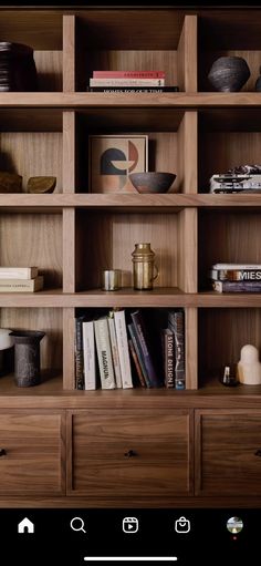 a wooden book shelf with many books on it and other items sitting on the shelves