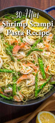 shrimp scampi pasta in a skillet with asparagus and lemon wedges