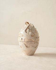 a white vase sitting on top of a table next to a brown object in the middle