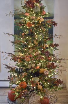 a decorated christmas tree with pumpkins and gourds on the top is lit up