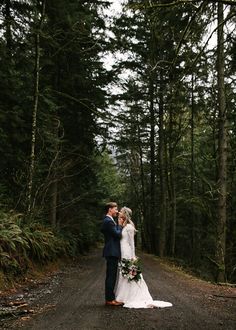 a man and woman standing in the middle of a forest