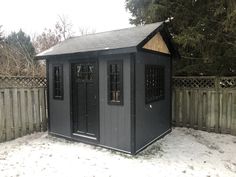 a small black shed sitting on top of snow covered ground