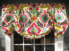 a window with a colorful flowered valance hanging from it's side