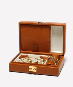 an open brown leather box with jewelry in it on a white background, there is also a ring and bracelet inside