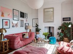 a living room with pink couches and pictures on the wall above it, along with other furniture