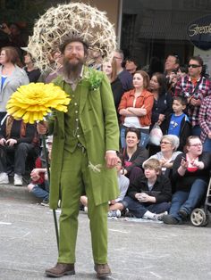 a man in green suit holding a yellow flower and standing next to a group of people