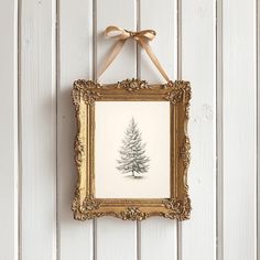 an ornate gold frame hangs on a white wall with a pine tree drawn in it