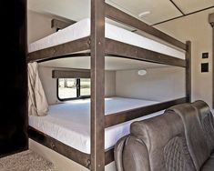 a bunk bed in the corner of a room with a couch and chair next to it