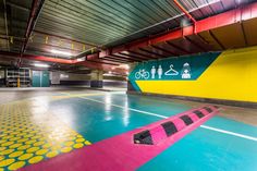 an empty parking garage with colorful flooring and neon colored signs on the wall above it