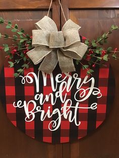 a wooden sign that says merry and bright hanging from a door with a bow on it