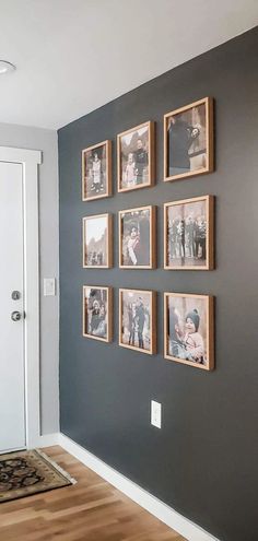 a wall with many pictures hanging on it and a rug in front of the door