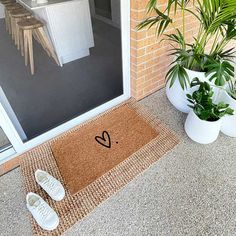 a pair of white slippers sitting on top of a door mat next to a potted plant