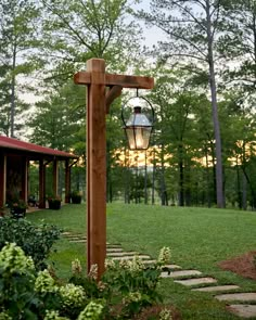 a wooden post with a lantern hanging from it's side in the middle of a yard