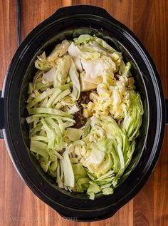 chopped cabbage in a slow cooker on a wooden table