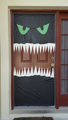 a door decorated to look like a monster with green eyes and fangs on it's face