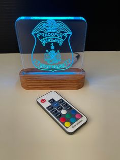 a remote control sitting on top of a table next to a light box with a logo