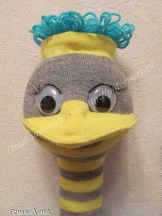 a stuffed bird with blue hair wearing a yellow and gray striped sock hat on it's head