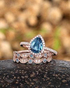 two wedding rings with blue topaz and white diamonds on a rock in front of some rocks