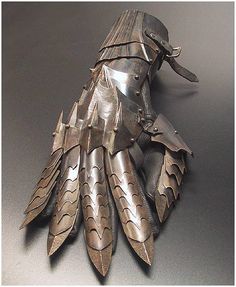 an intricately designed metal object on a gray surface with one hand holding the other