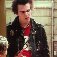 a young man wearing a leather jacket talking to someone