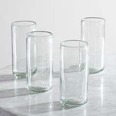 three clear glass vases sitting on top of a marble table next to each other