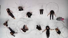 an aerial view of several people in black outfits and one is holding her arms out