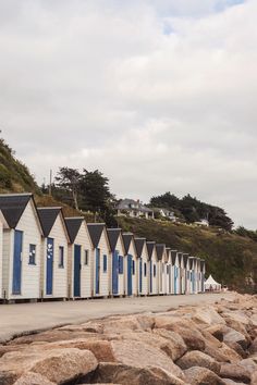 a row of beach huts sitting next to each other on top of a rocky shore