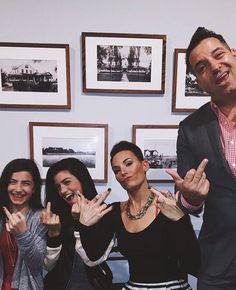 three women and one man are posing for the camera with their hands in the air