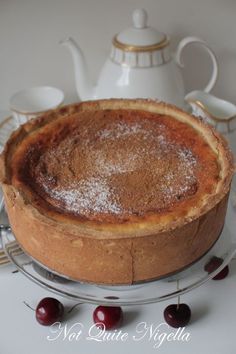 a cake sitting on top of a metal pan covered in powdered sugar and cherries