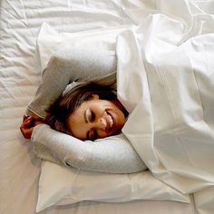 a woman is laying in bed with her head on the pillow and she's smiling