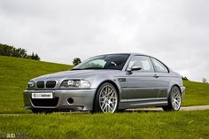 a silver car parked on the side of a road next to a lush green hillside