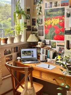 a laptop computer sitting on top of a wooden desk in front of a large window