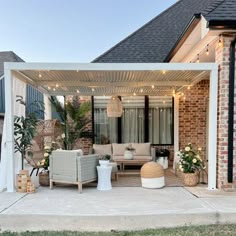 a patio covered in furniture and lights next to a brick building with an awning