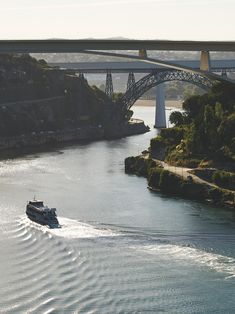 a boat traveling down the river under a bridge