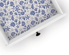 an open white box with blue and white wallpaper on the bottom, underneath it