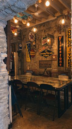 a table and chairs in a room with lights hanging from the ceiling above it, along with signs on the walls