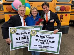 three people standing in front of a school bus holding up large checks for $ 1 million